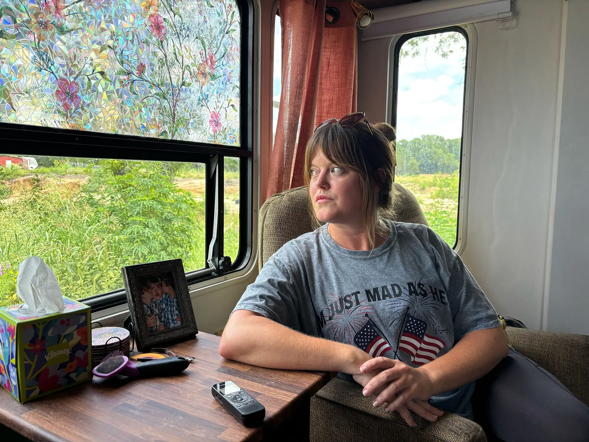A woman sits in a mobile home looking out a window