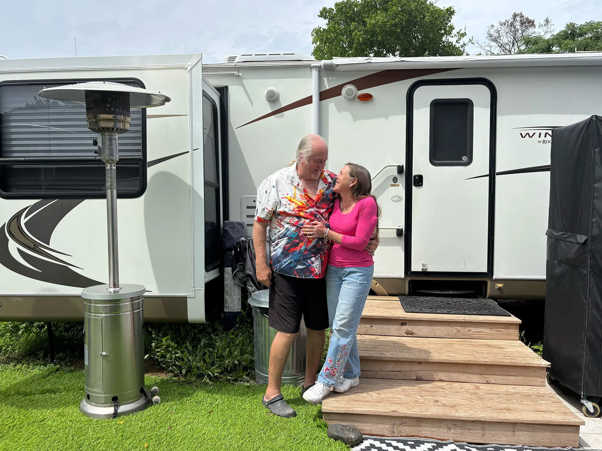 A couple in later middle age stand in front of an RV
