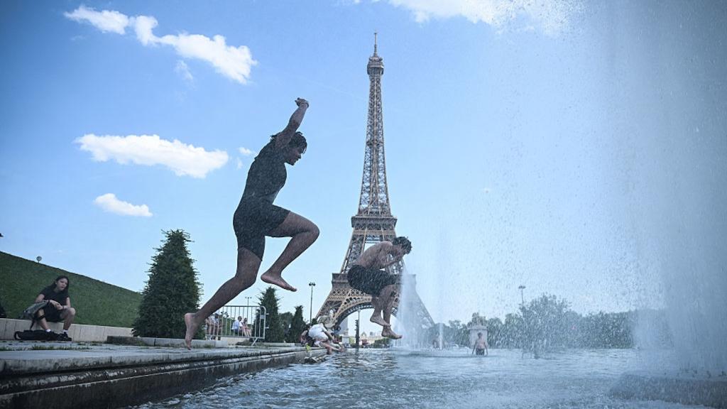 men jumping into water in front of Eiffel tower