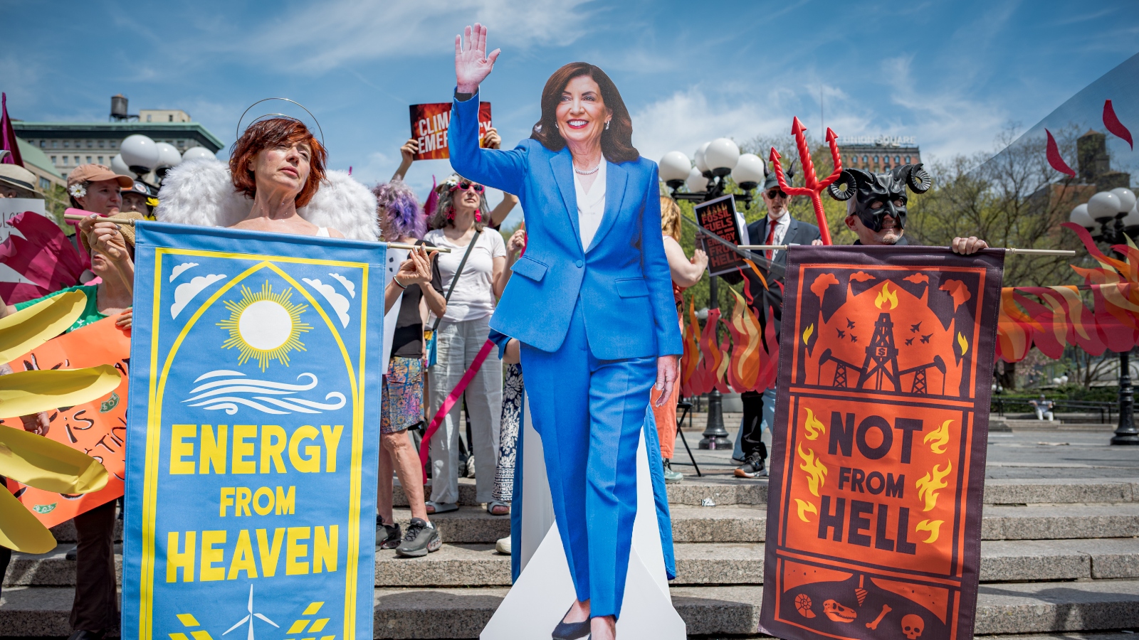 Protestors hold signs and a cutout of New York Governor Kathy Hochul at a protest against the governor's efforts to weaken the state's landmark climate law.
