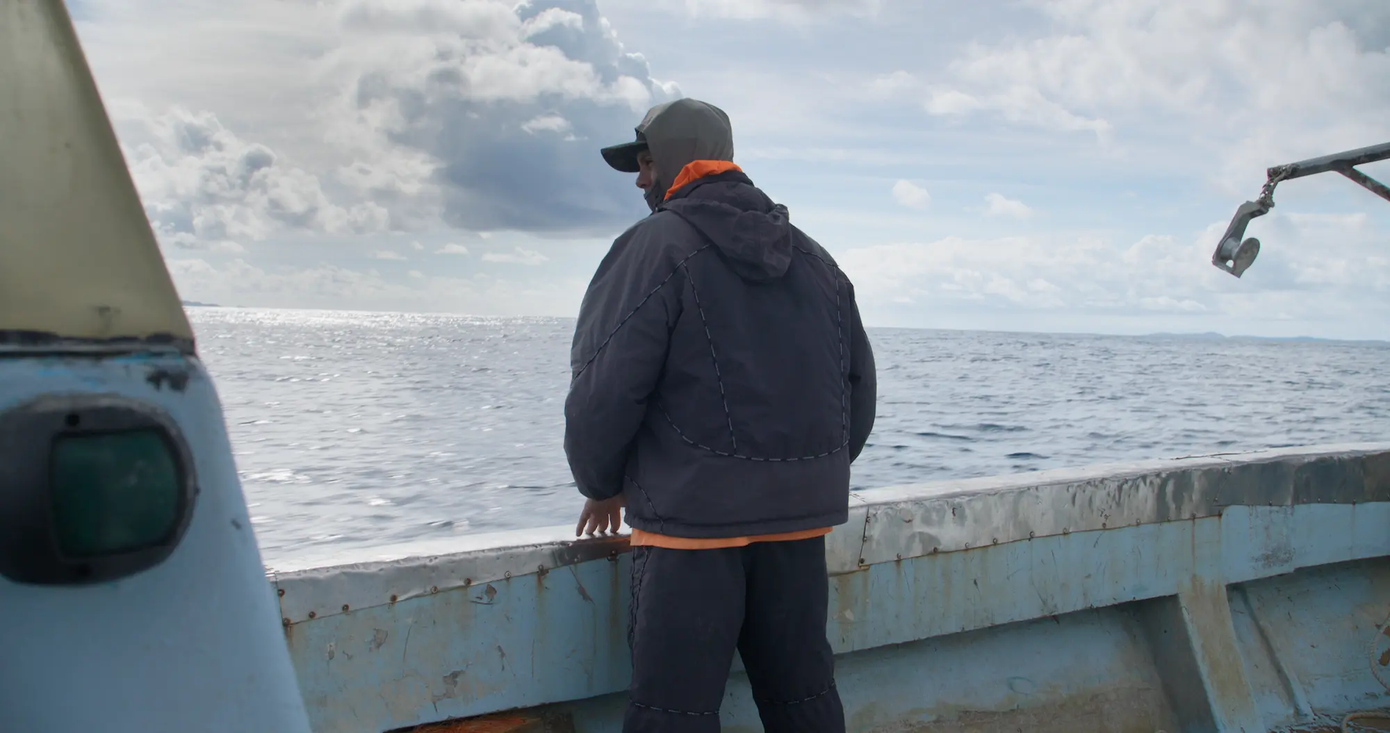 A man stands near the side of a fishing boat