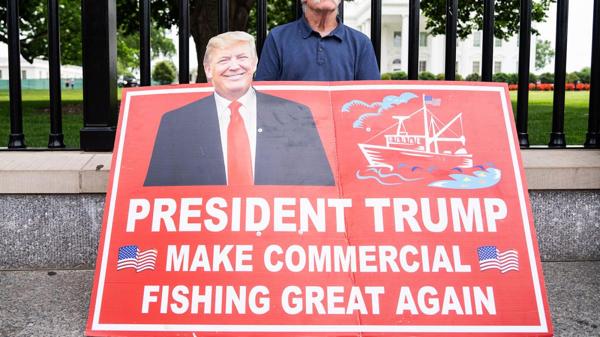 man holding a sign that reads President Trump make commercial fishing great again