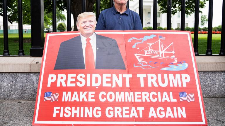 man holding a sign that reads President Trump make commercial fishing great again