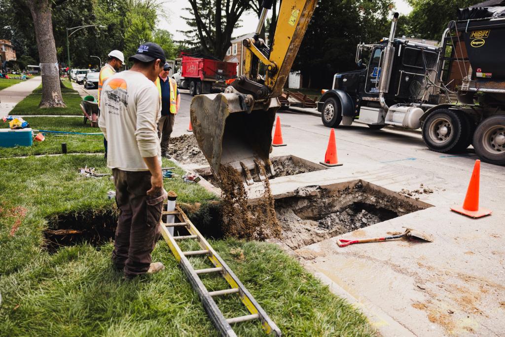 workers remove a lead service line from a residential house