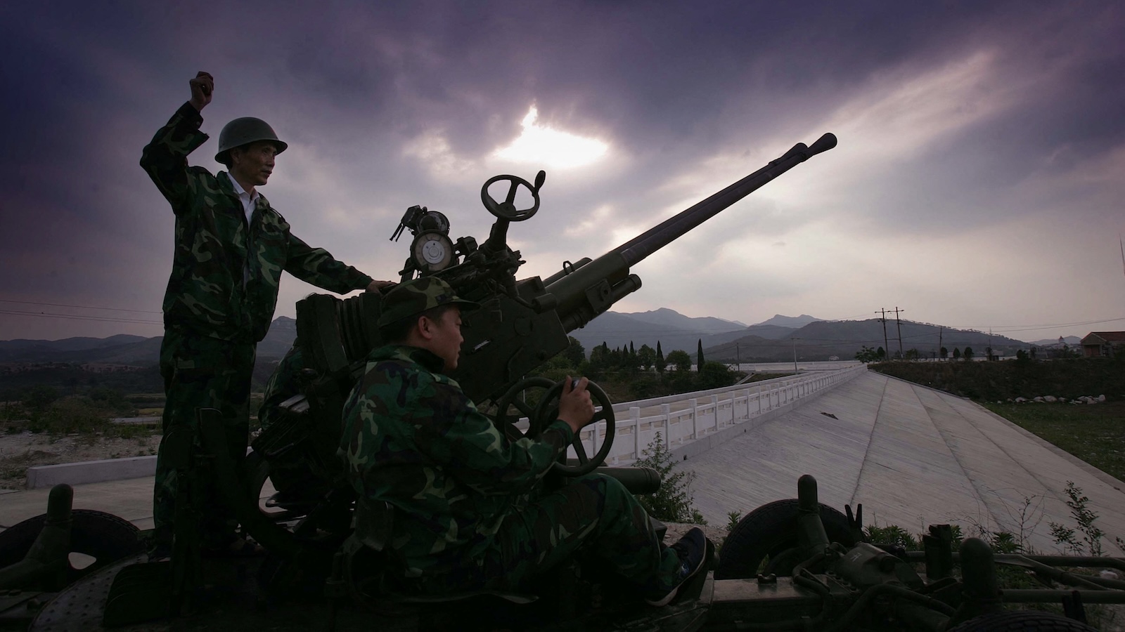 A man signals to another man to fire a seed-clouding rocket.