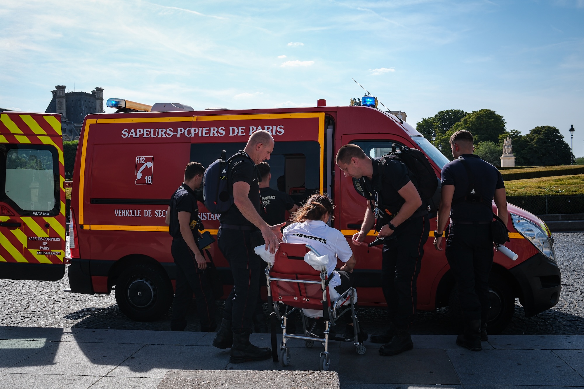 people in blue uniforms load a person on a stretcher into an ambulance with french writing on the side