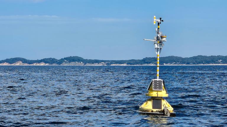 Floating yellow weather station buoy on blue Lake Michigan.