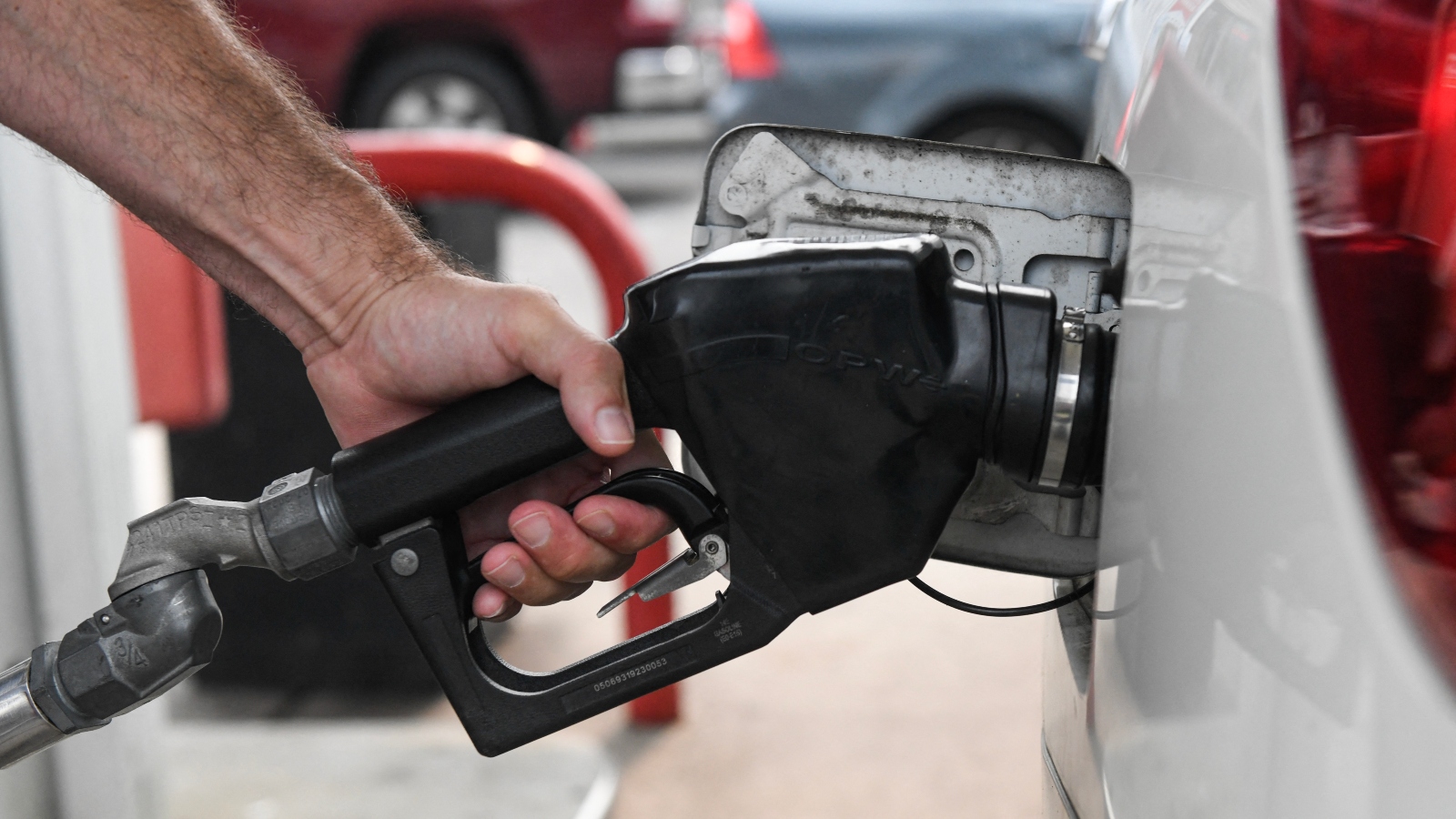 A man's hand holds a gas pump