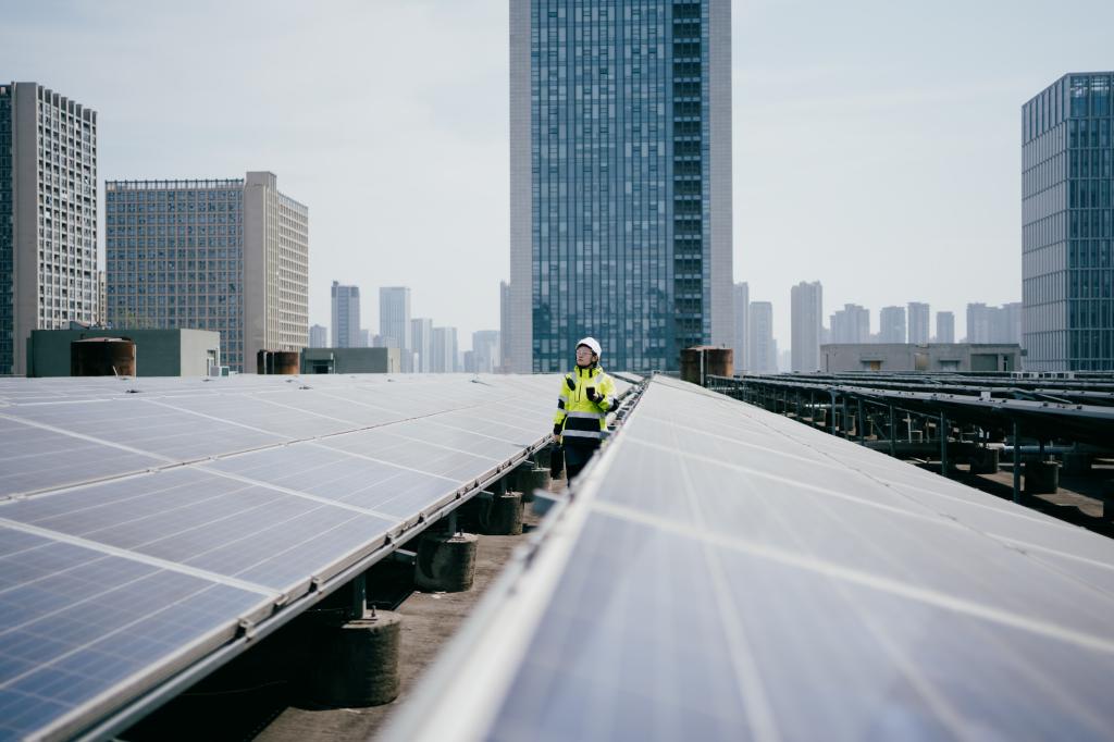 A neon-vested technician walks among solar panels in China