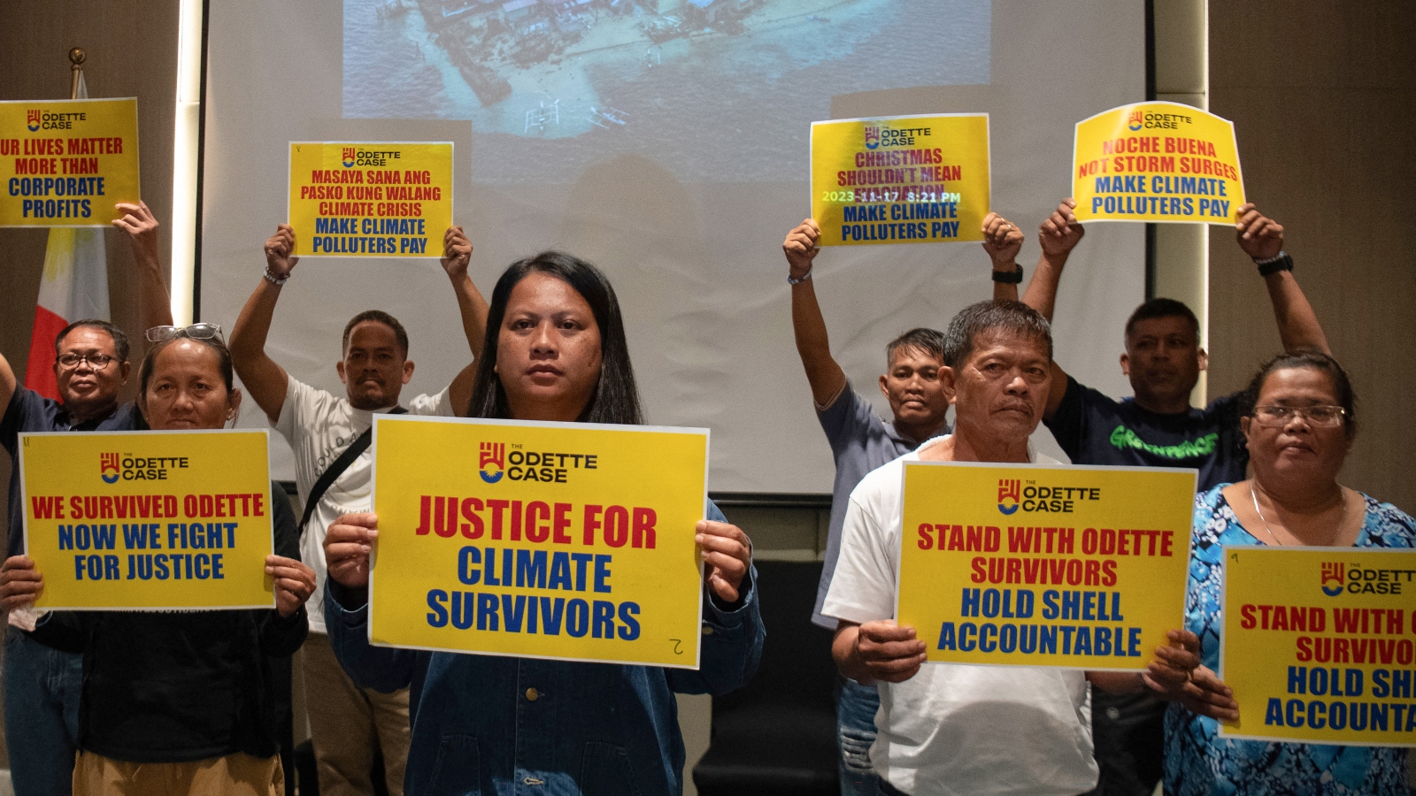 A group of people hold up justice for climate survivors signs
