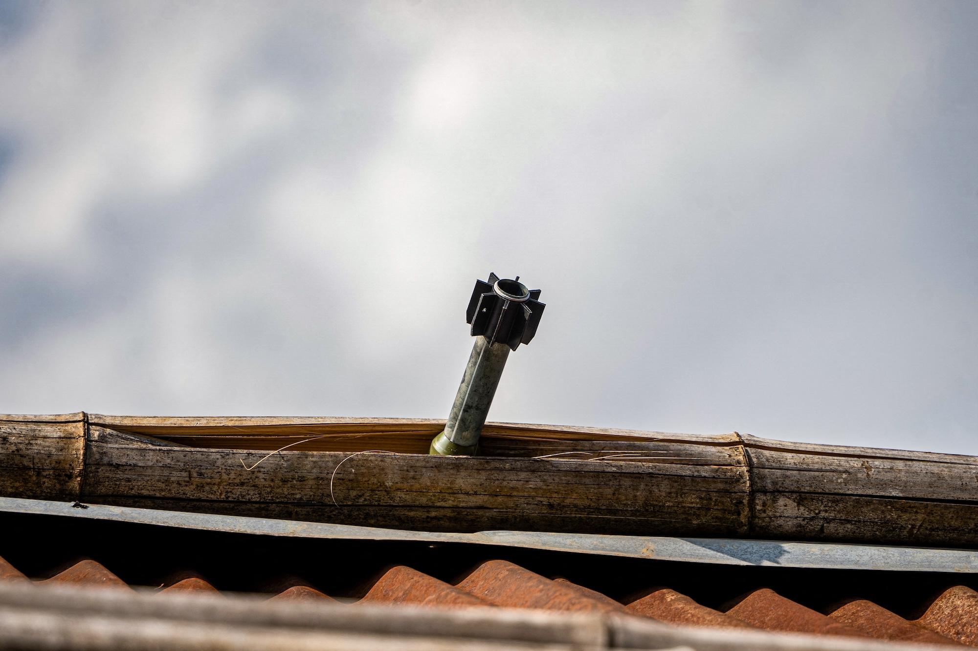 An unexploded projectile sticks out of a piece of roofing