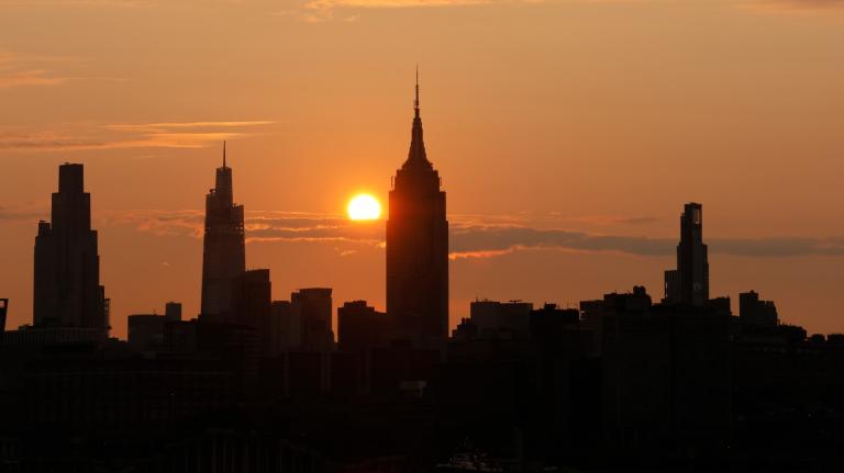 The sun behind the NYC skyline