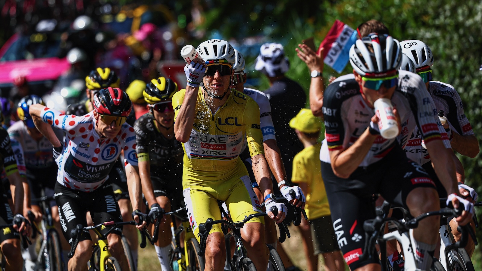 A line of cyclists competing in the Tour de France douse themselves with water to stay cool.