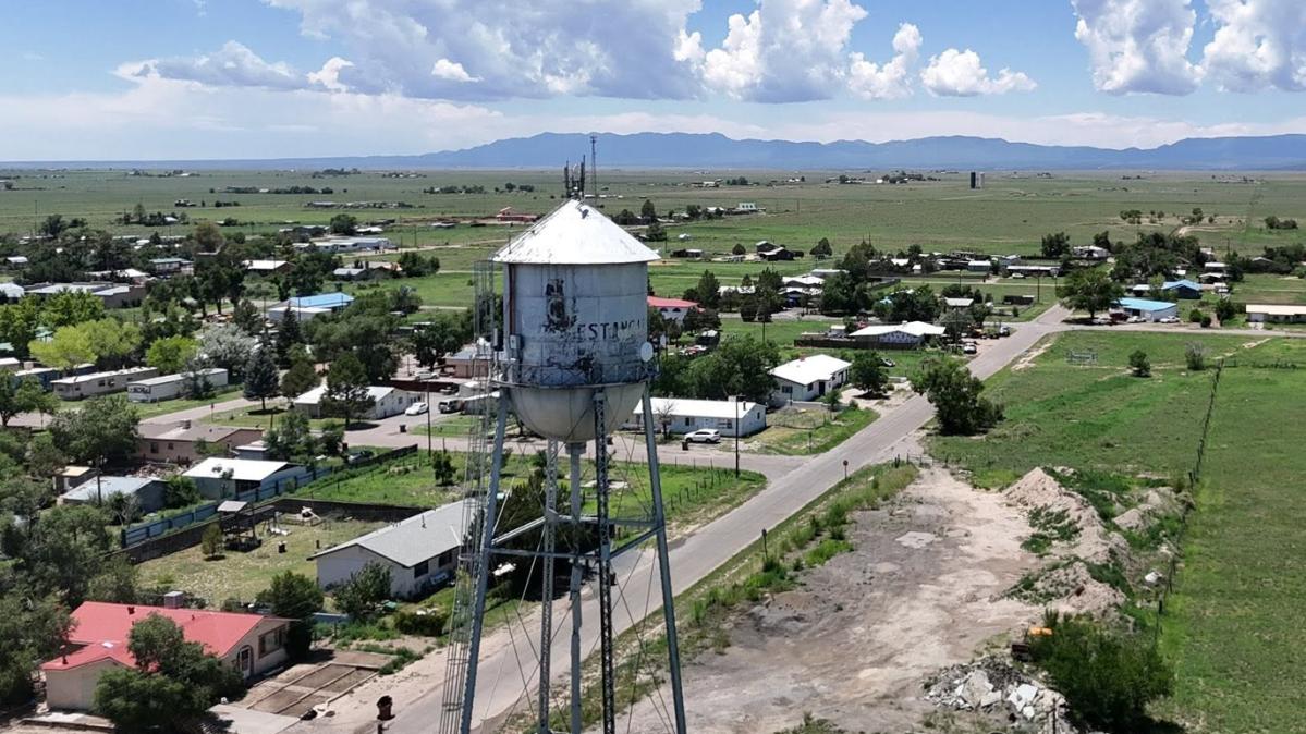 A water tower stands next to a small desert town