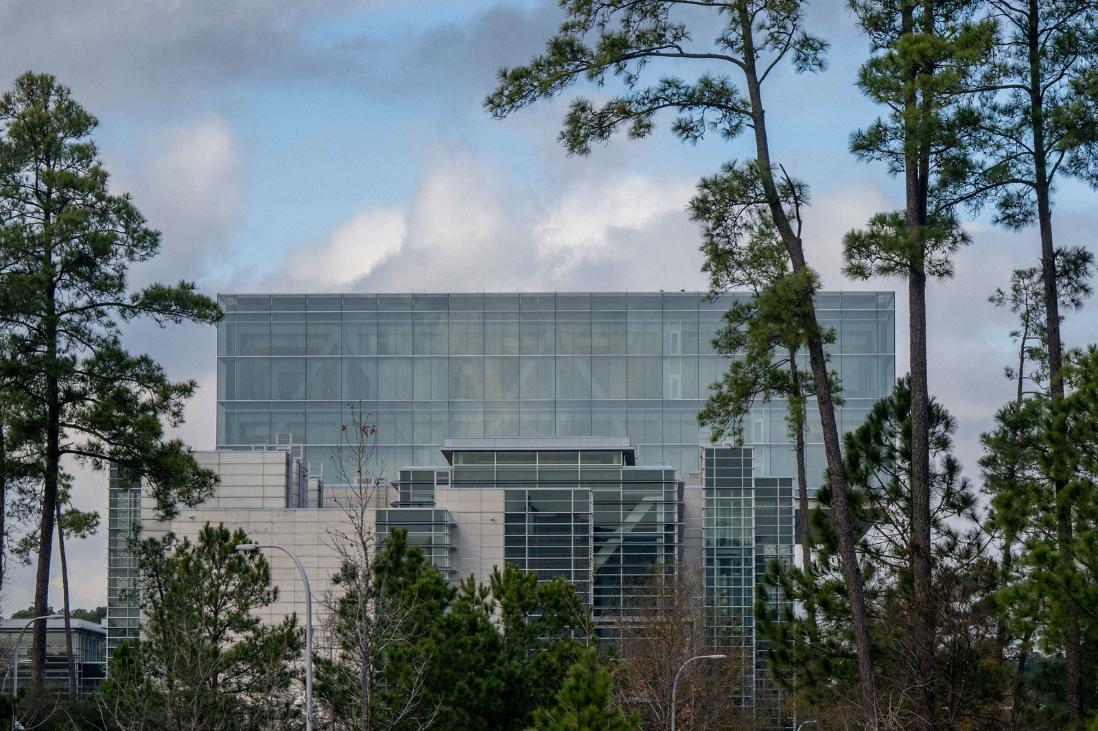a mostly glass building with a few trees planted in front