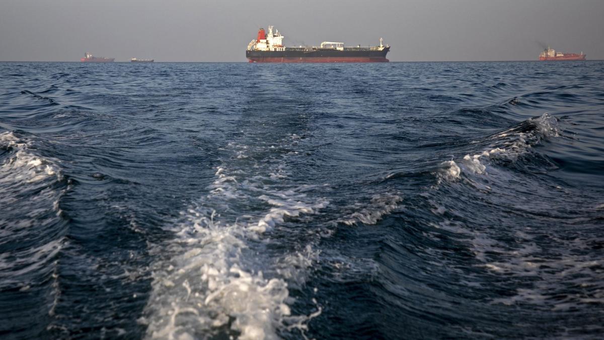 large container ships and oil rigs seen anchored in a churning waterway