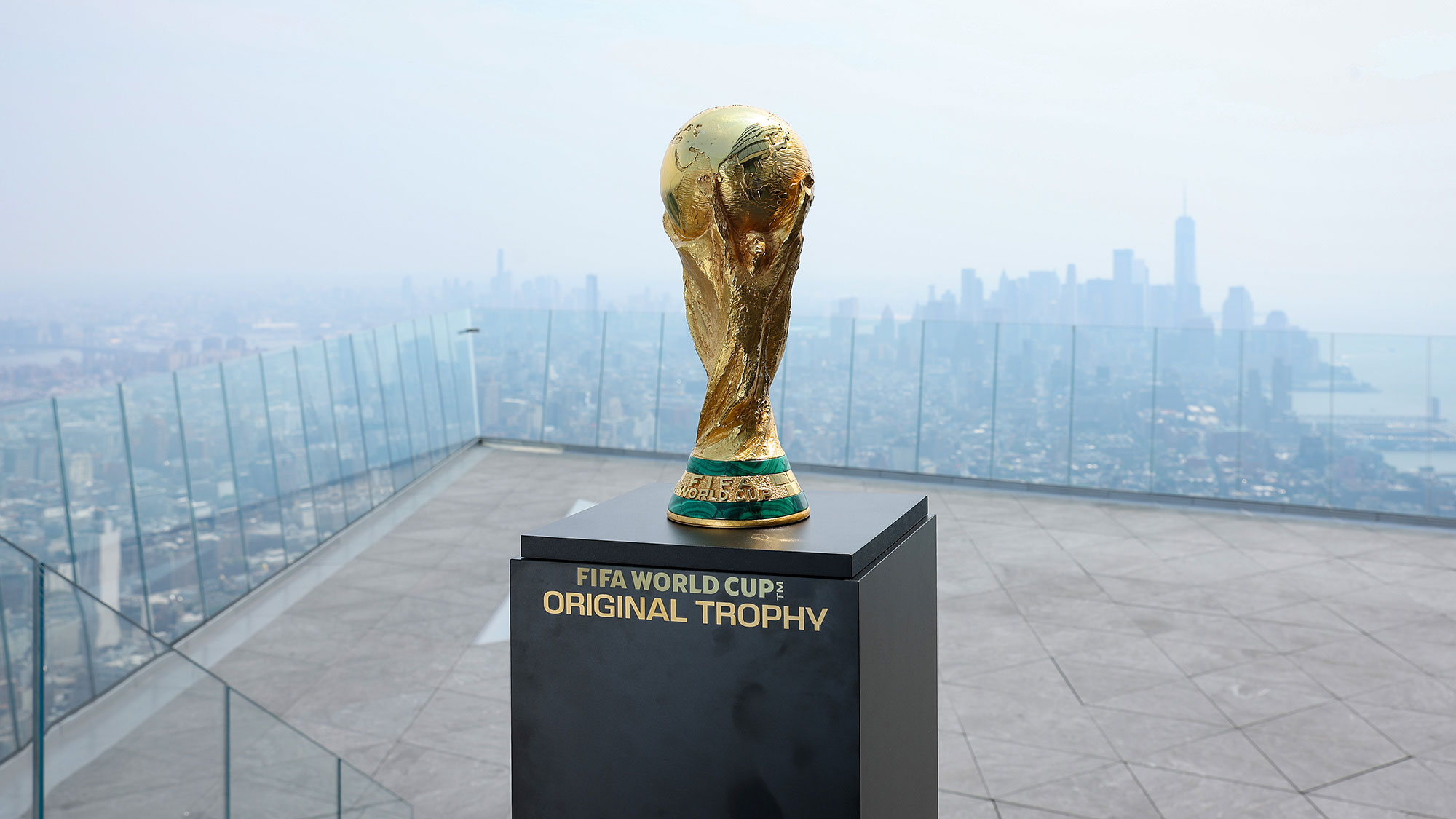World Cup trophy on pedestal in front of city skyline filled with wildfire smoke