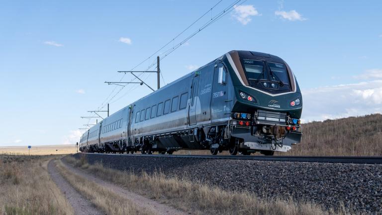 A new Amtrak Airo train, built for the Amtrak Cascades route, moves across an open landscape.