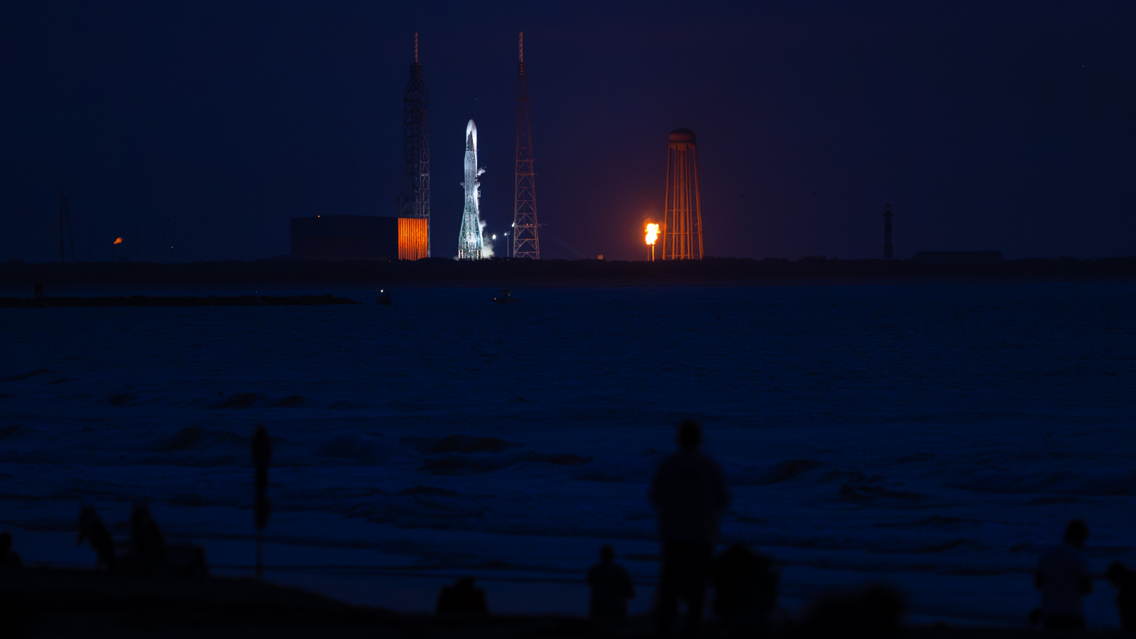 Photo of people watching a rocket launch at night