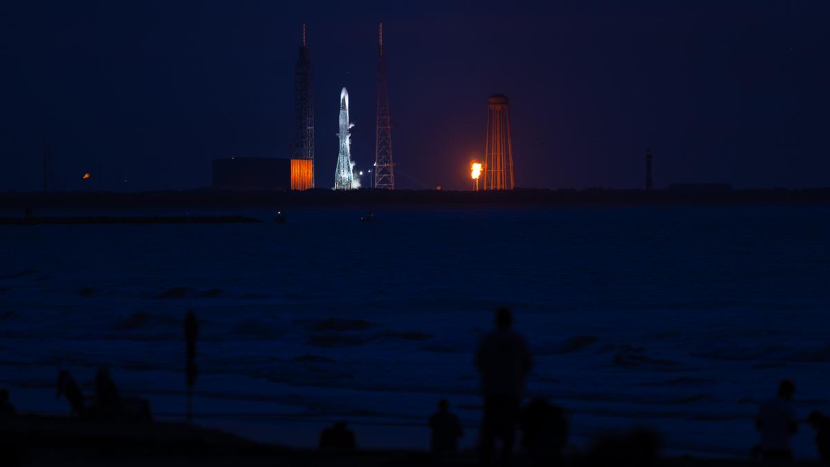 Photo of people watching a rocket launch at night