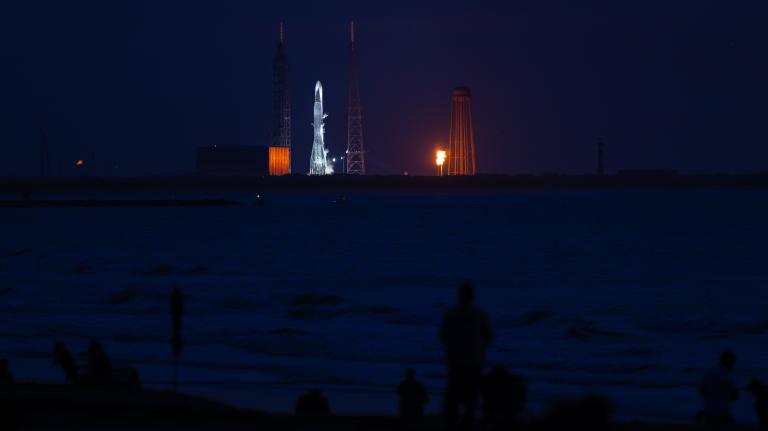 Photo of people watching a rocket launch at night