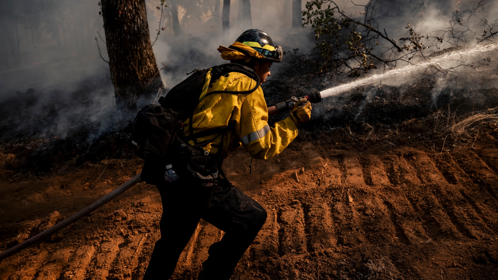 A firefighter holds a hose shooting water