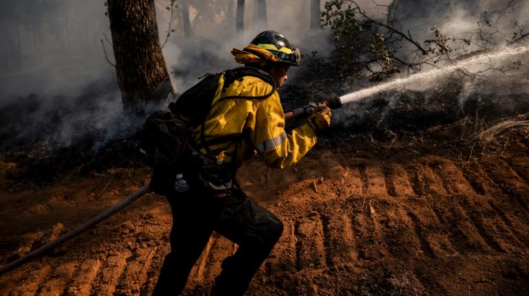 A firefighter holds a hose shooting water