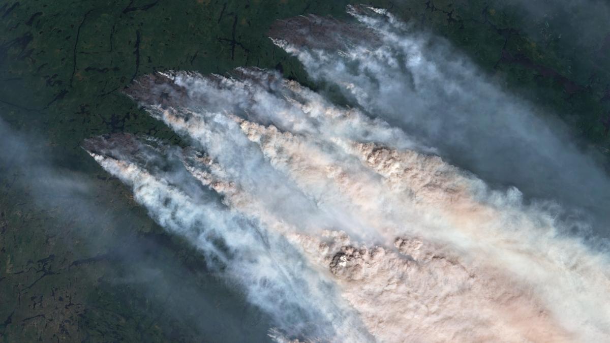 A satellite image shows enormous clouds of smoke rise from a forest burning in northwestern Ontario.