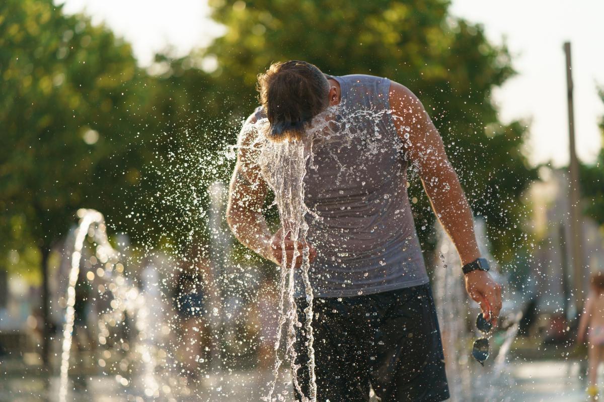 man sticks head in water fountain