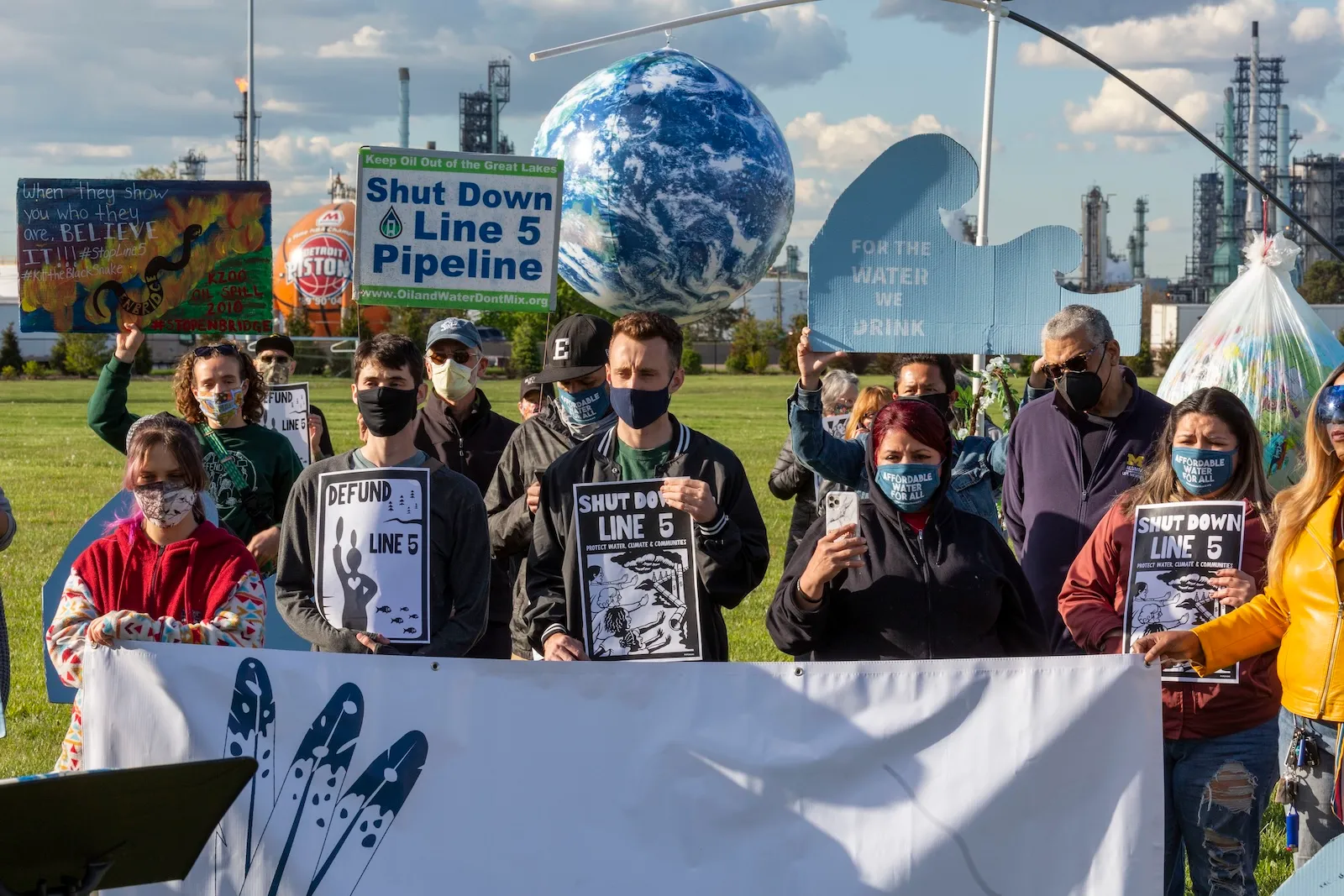 Protesters stand with signs saying Shut Down Line 5 Pipeline and For the Water We Drink
