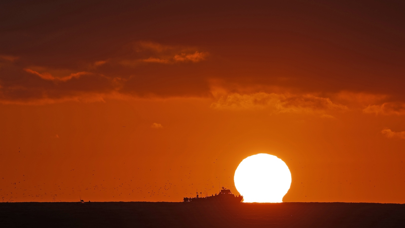 silhouette of a ship against a sunset on the sea