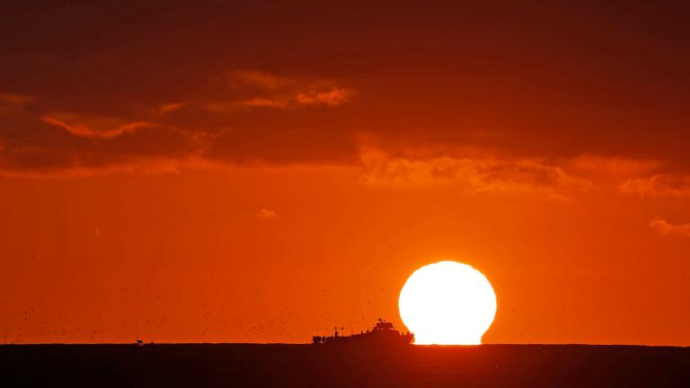 silhouette of a ship against a sunset on the sea