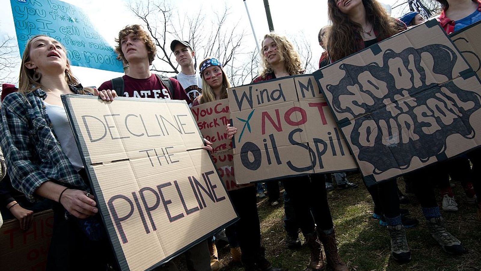 people stand with signs protesting pipeline