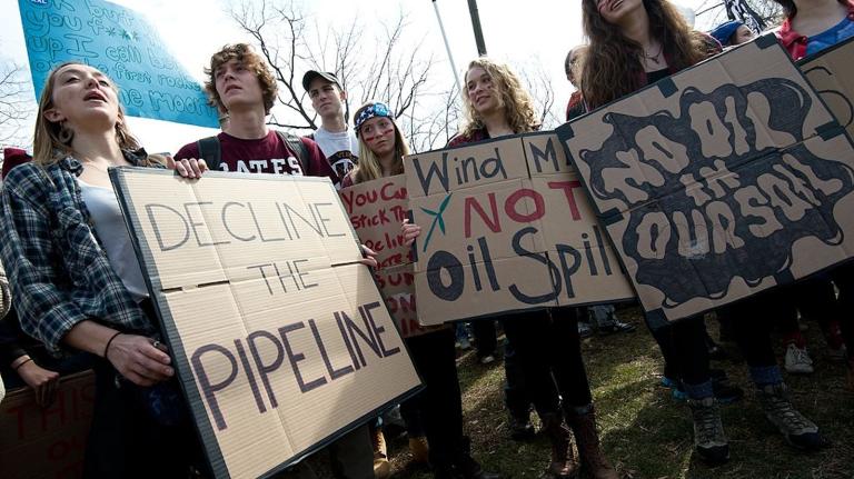 people stand with signs protesting pipeline