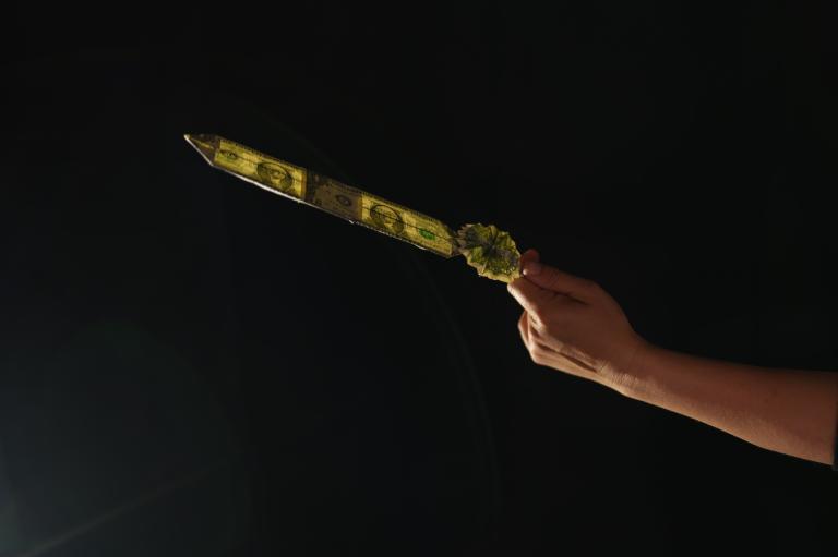 A hand holds out a feather made of two dollars folded bills