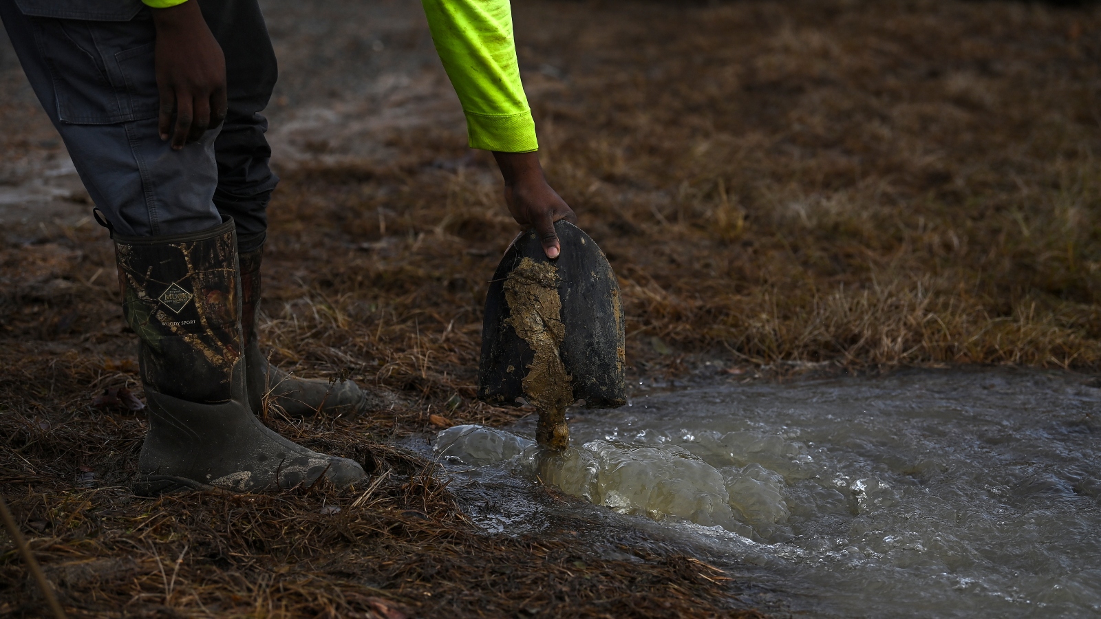 A man holds a shovel in a pool of water