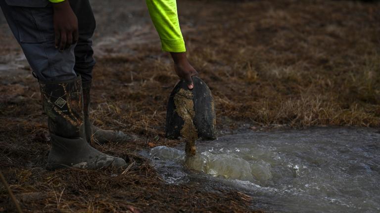 A man holds a shovel in a pool of water