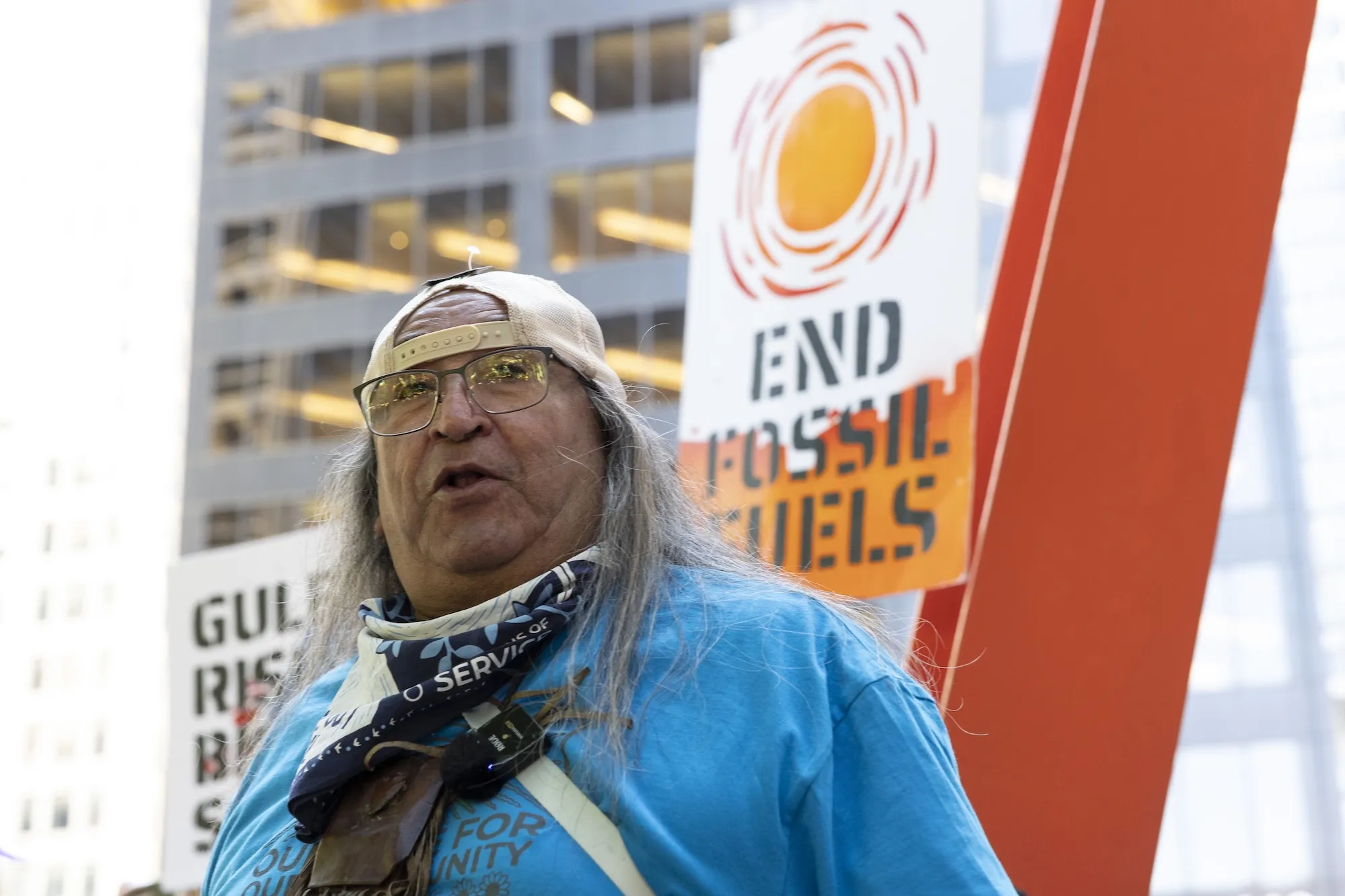 Juan Mancis stands in front of a banner that says 'end fossil fuels'