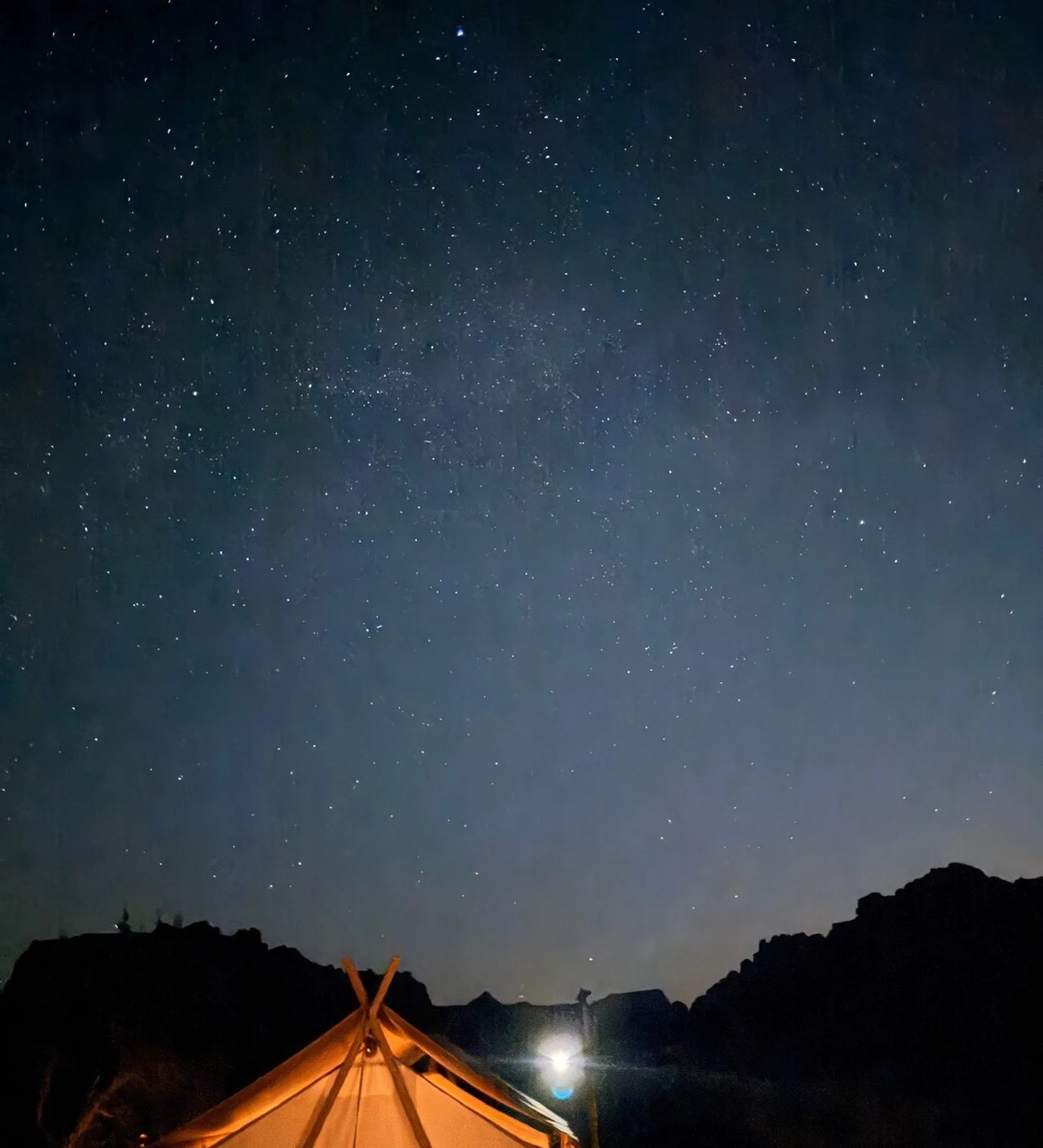 Stars at Zion national park over a warmly lit tent