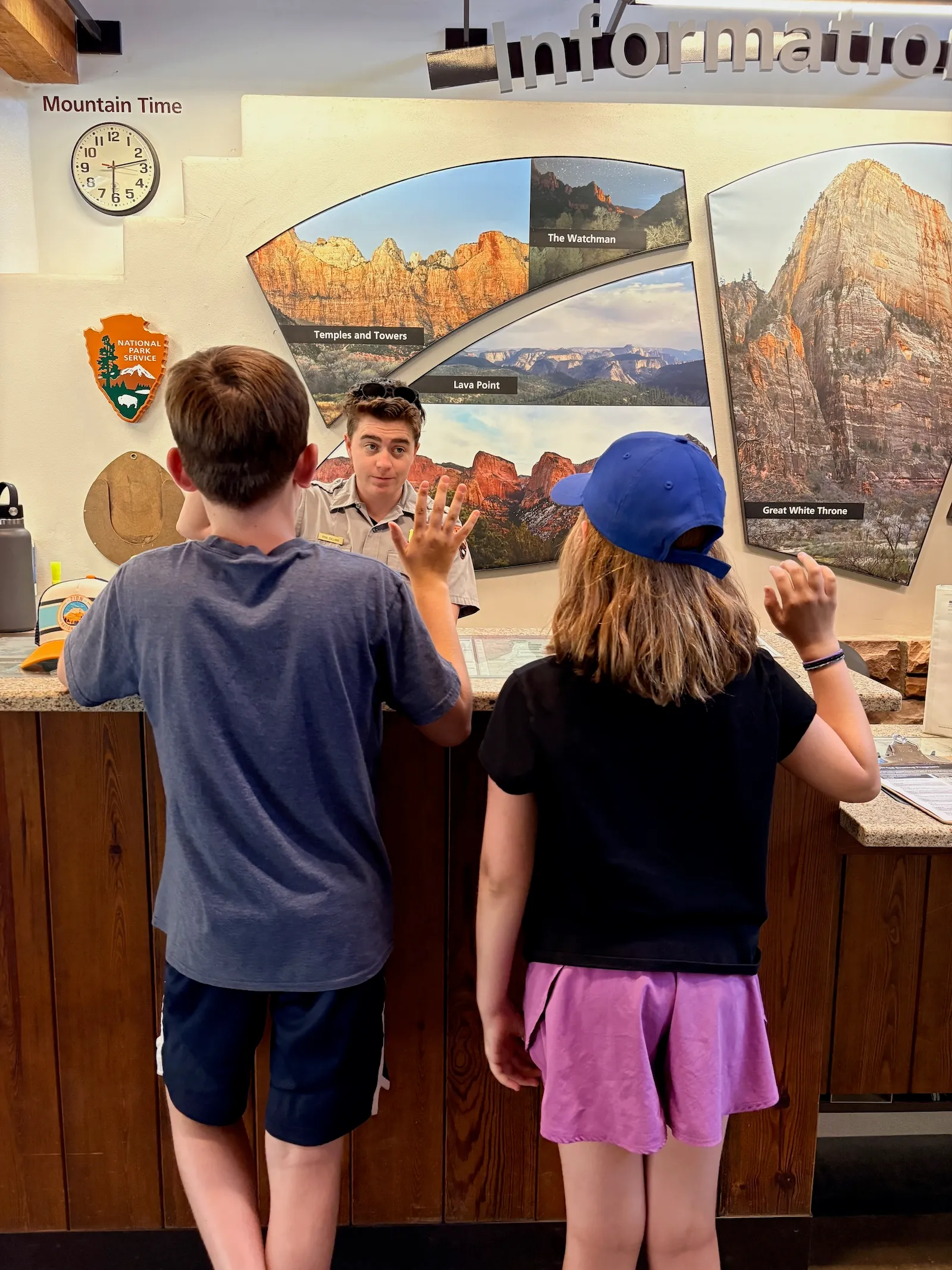 two children face a park ranger with their hands raised