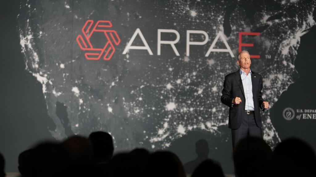 man standing on stage with map of USA behind him with text reading ARPAE