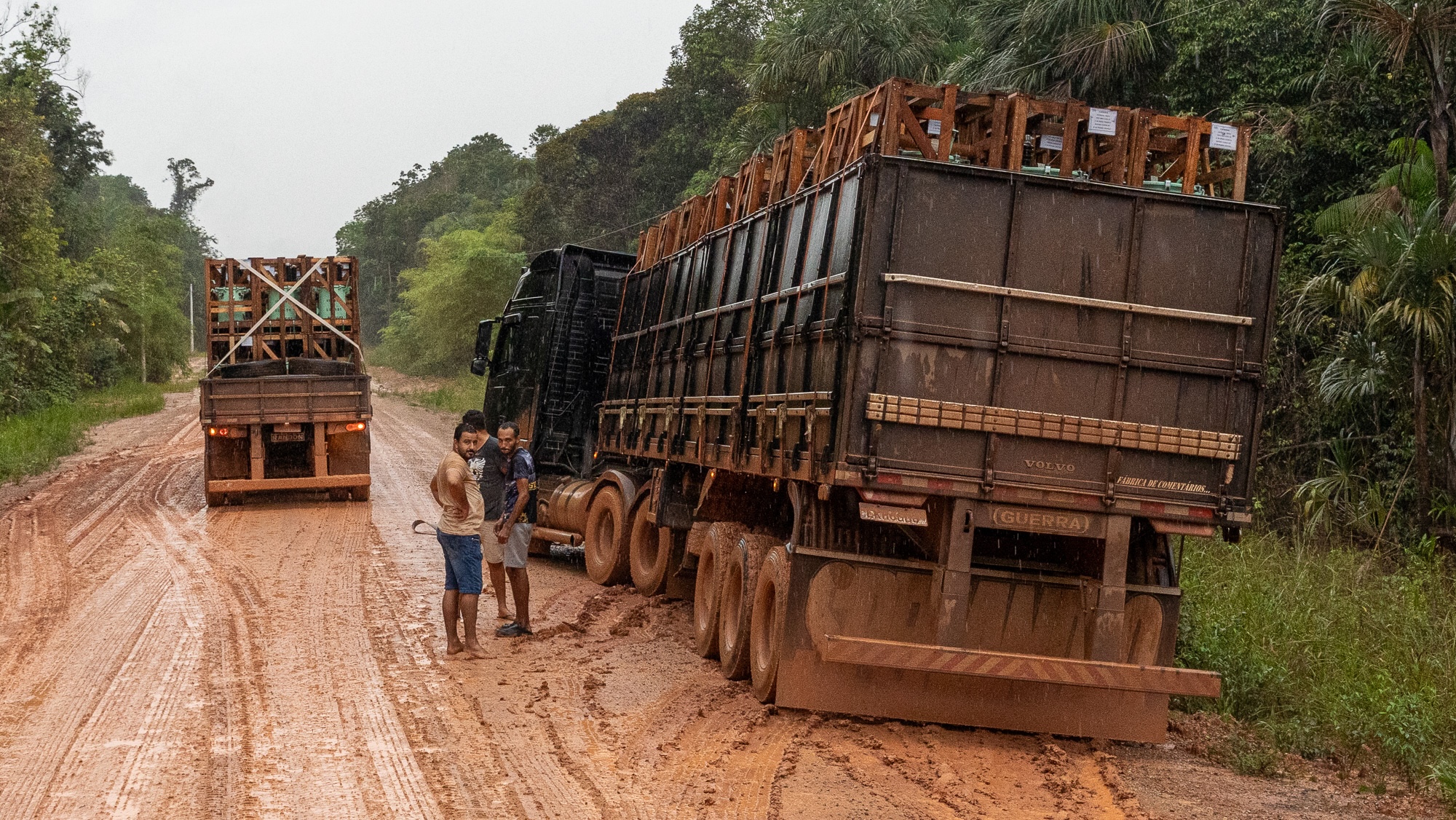 men stand by a truck near the side of an unpaved road in the amazon