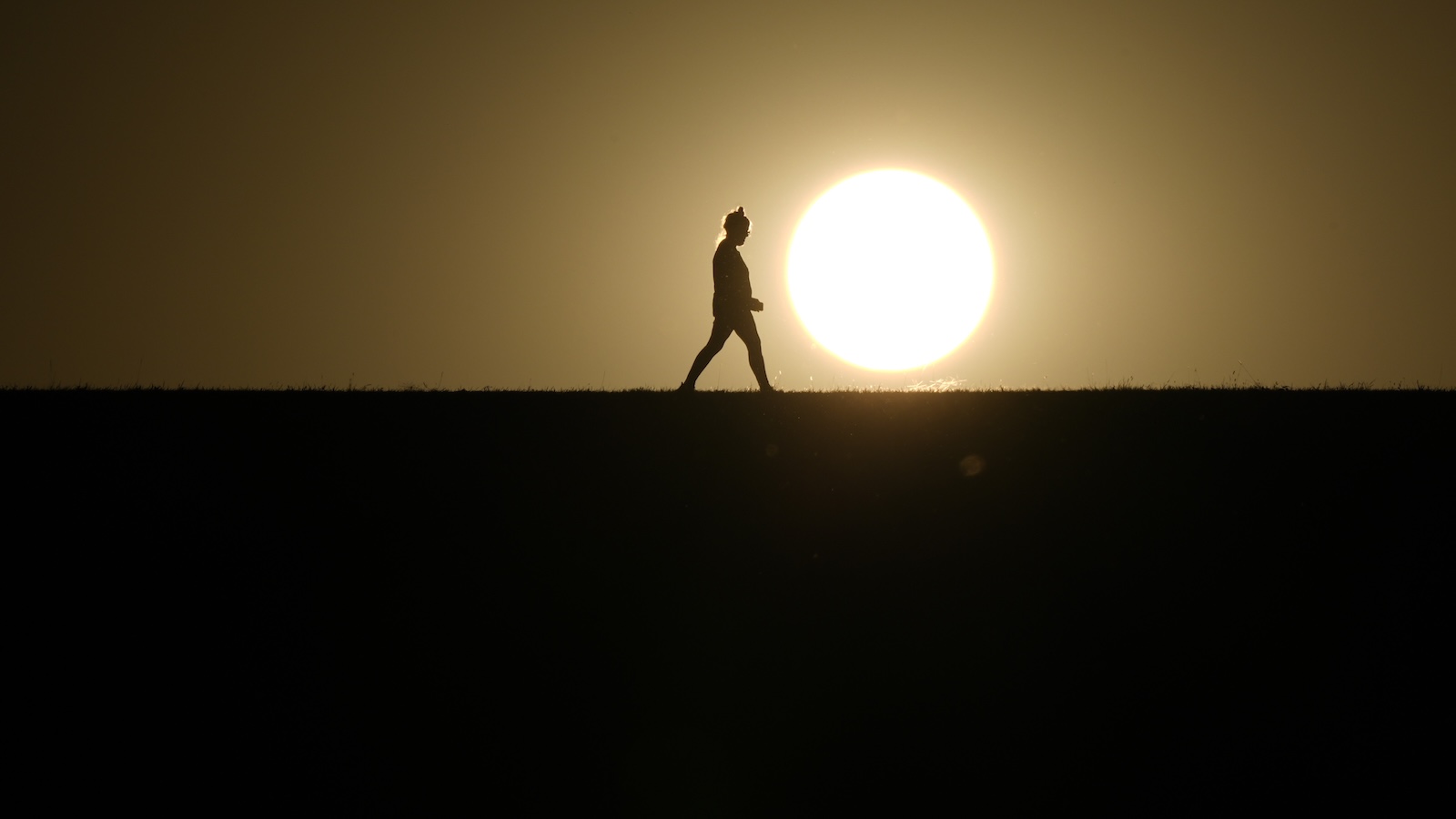 A person walks on a path during sunset on Monday, Sept. 30, 2024, in Omaha, Nebraska.