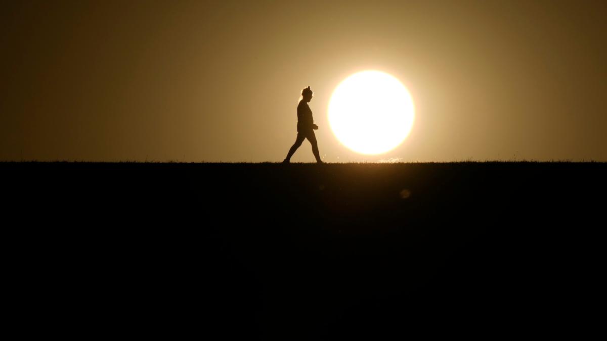 A person walks on a path during sunset on Monday, Sept. 30, 2024, in Omaha, Nebraska.