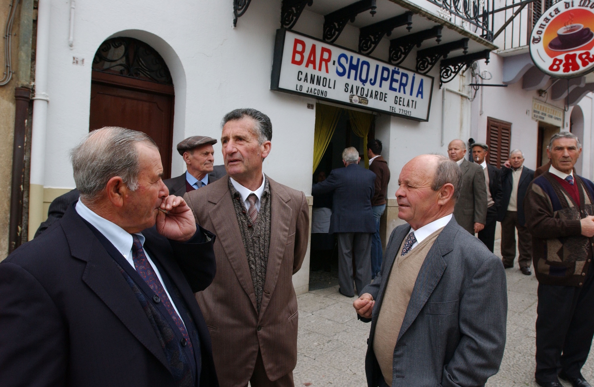 Mean in suits gather near a cannoli shop in Sicily