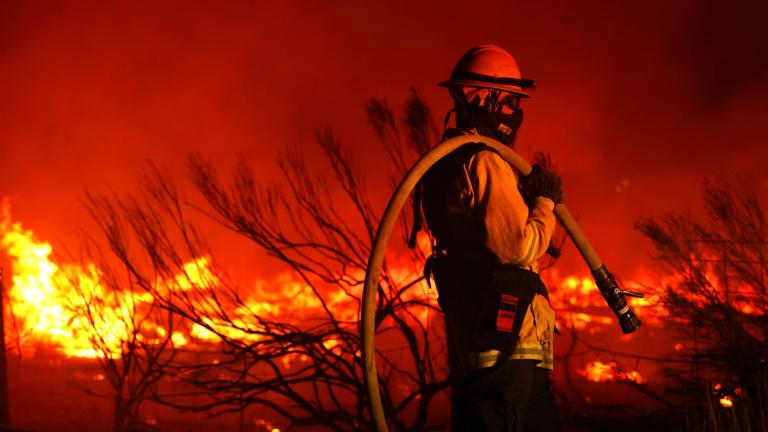 A firefighter monitors the Dixie Fire as it burns close to a home on August 16, 2021 near Janesville, California