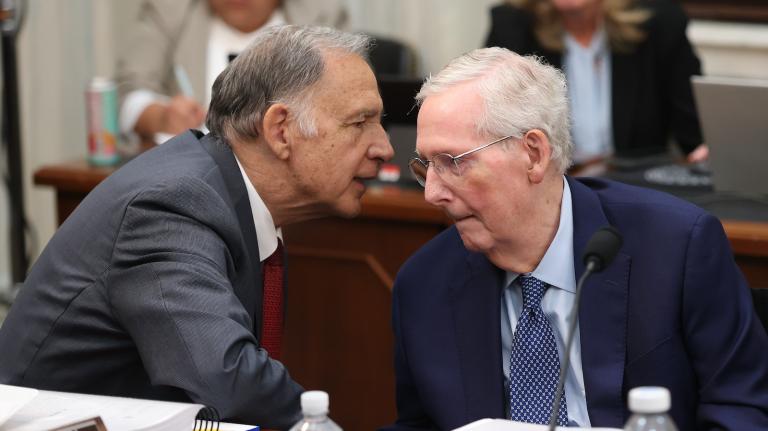 Senator John Boozman leans over and appears to whisper something to Senator Mitch McConnell at a Senate Agriculture Committee meeting.