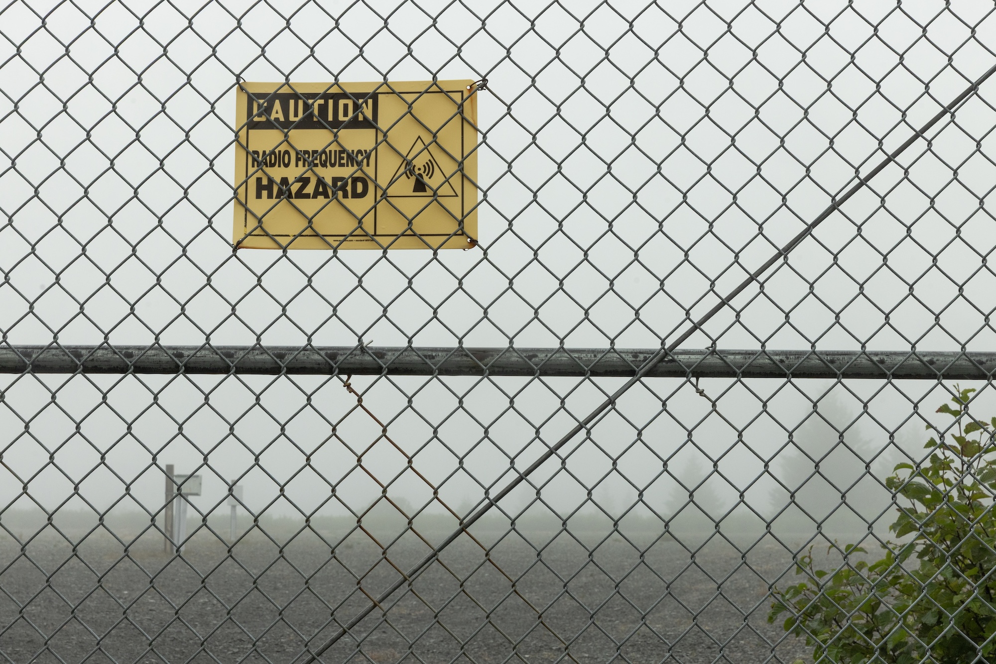 a hazard sign near a metal fence
