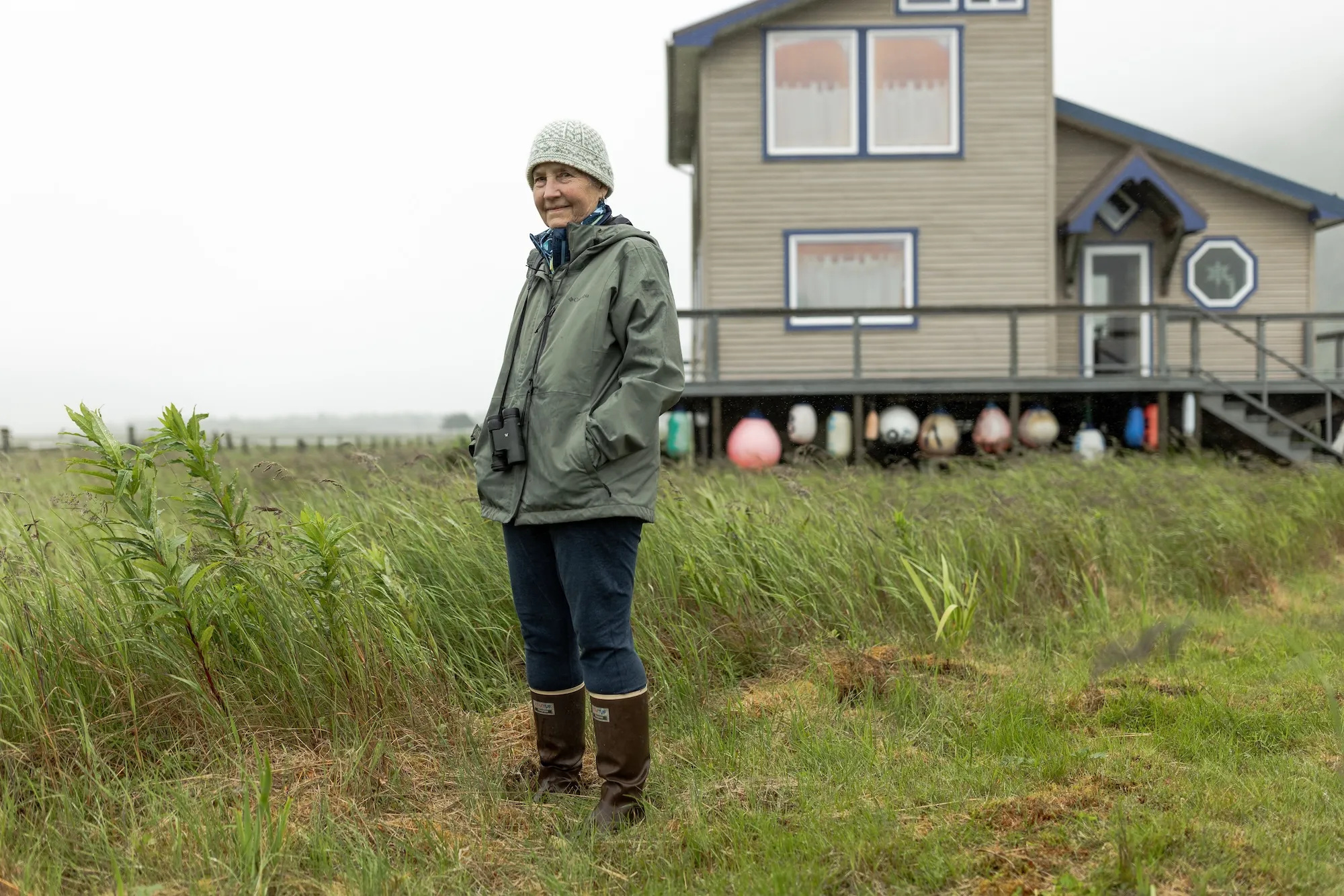 A woman in wellies stands near a cabin