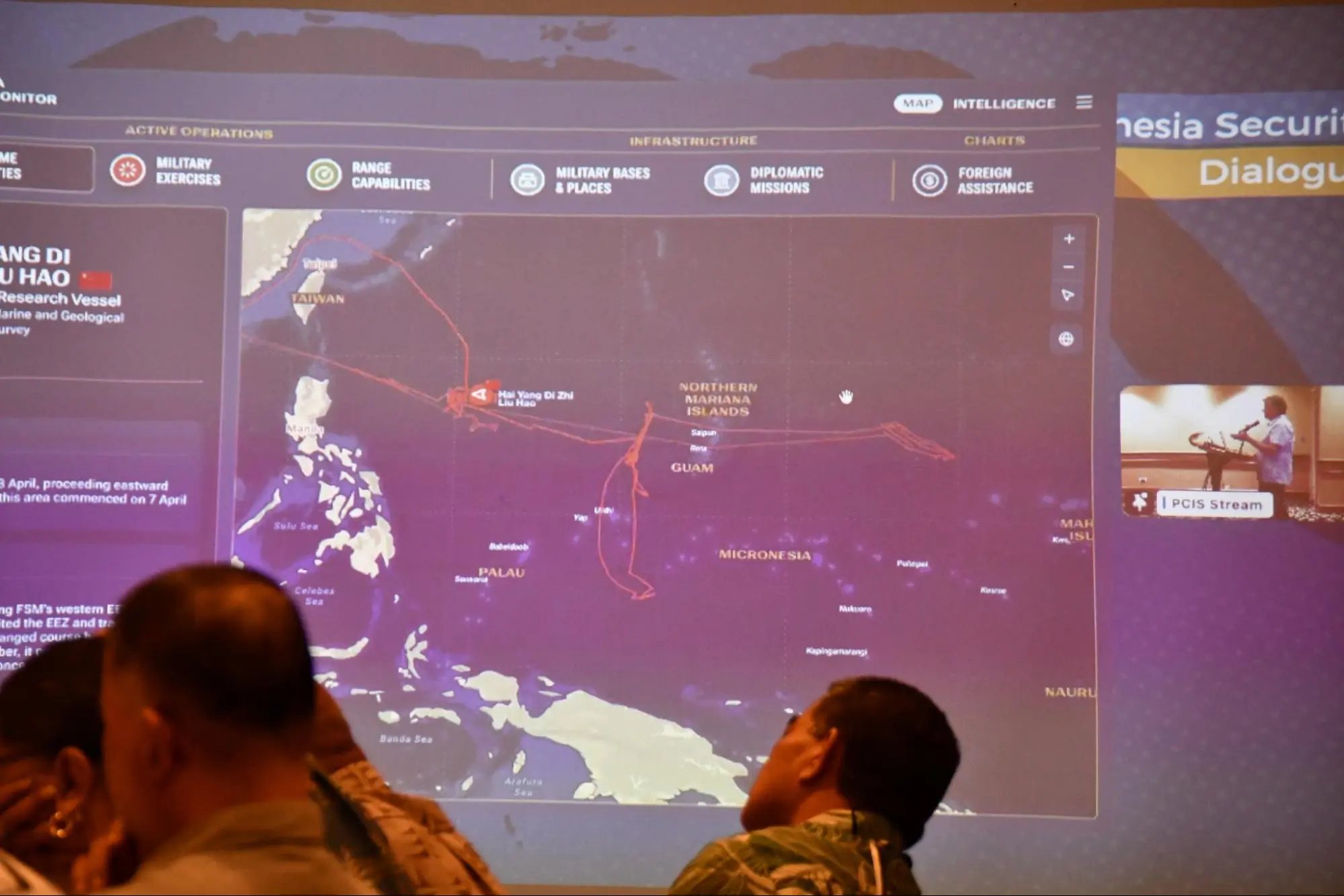 A man watches a large full-wall screen with a map of Guam on it